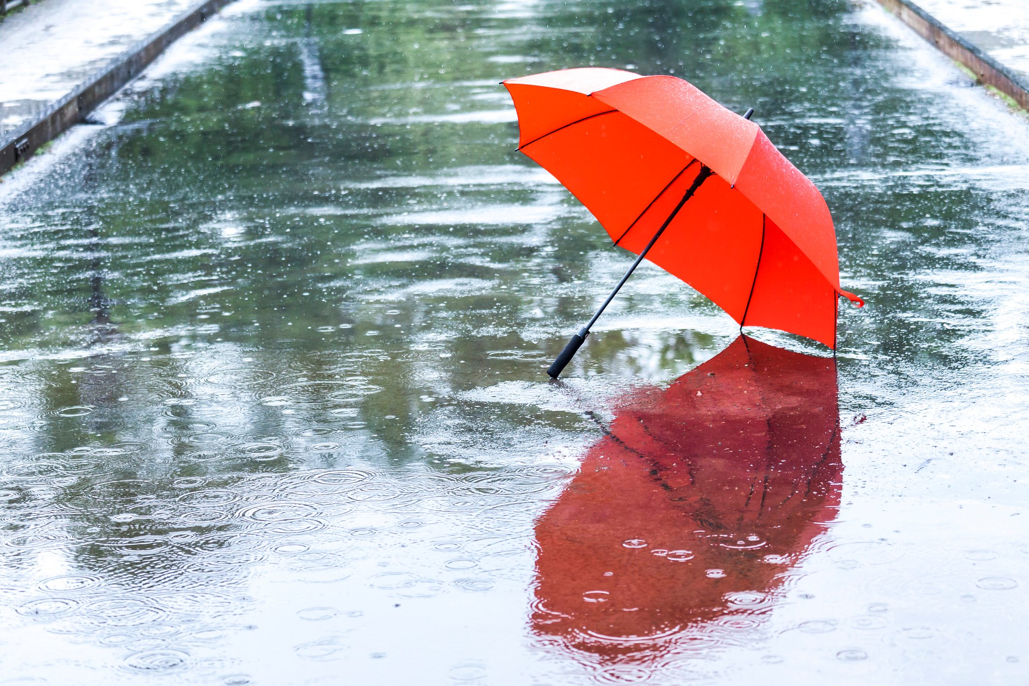 Rain falling on a red umbrella on an empty street 