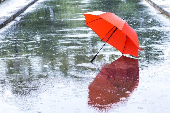 Rain falling on a red umbrella on an empty street 