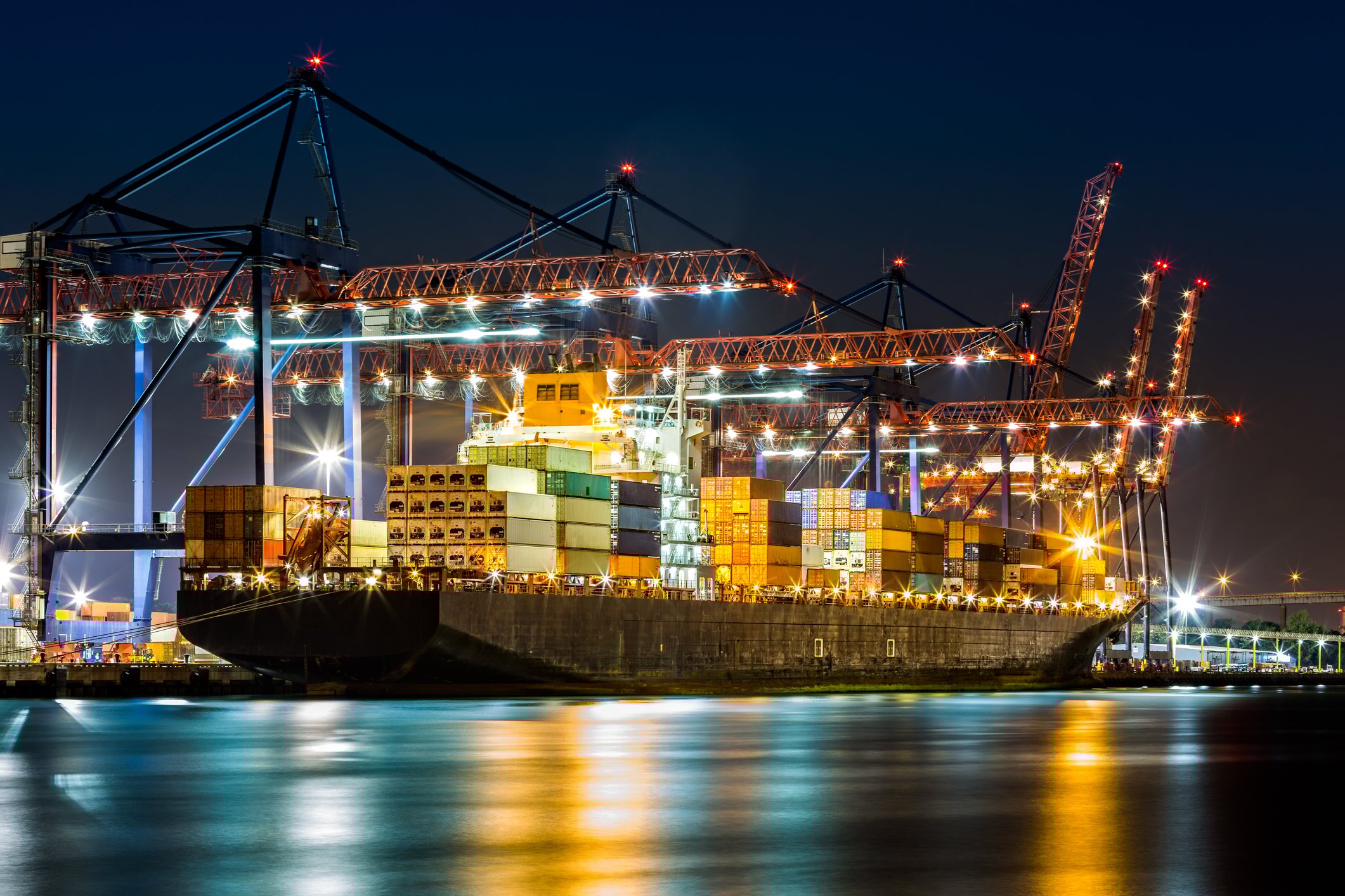 A container ship in a port at night.