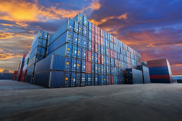 Stacks of blue and red stacked industrial containers at dusk.