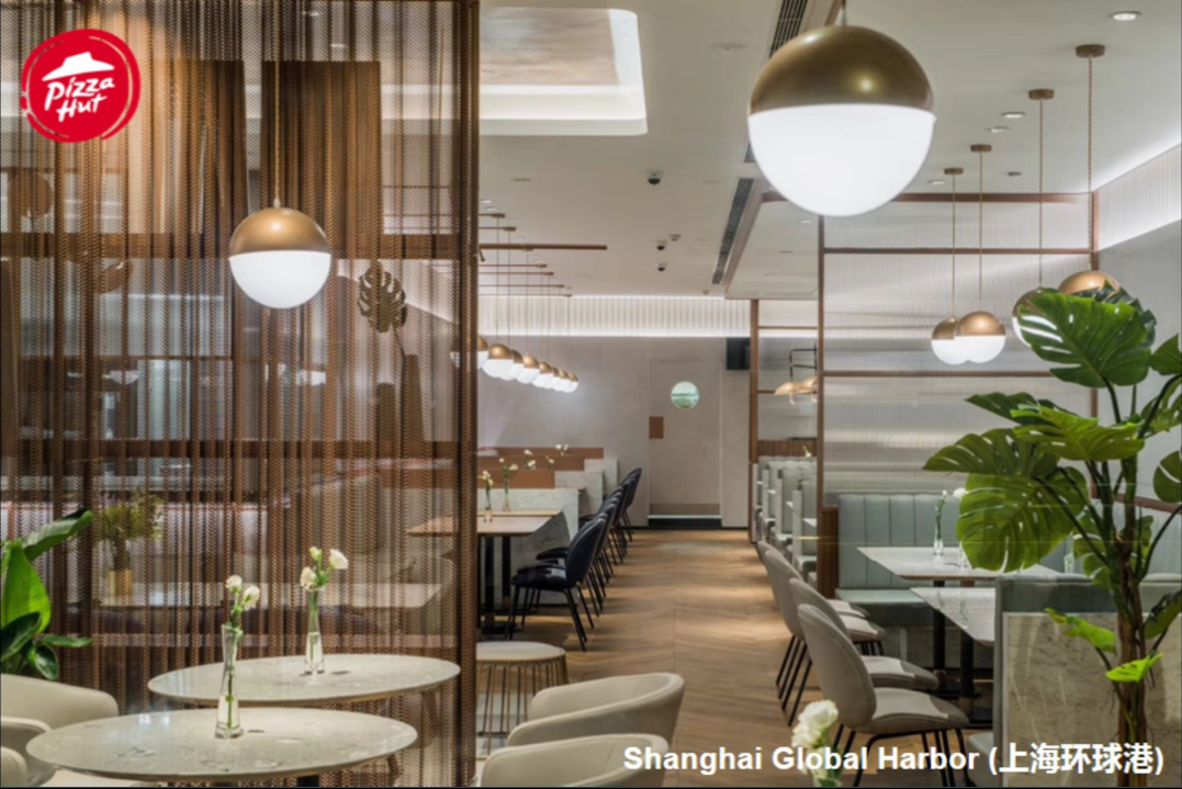 The interior of the new Shanghai Pizza Hut. Chairs and walls are in neutral white with soft neutral brown accents and modern lighting.