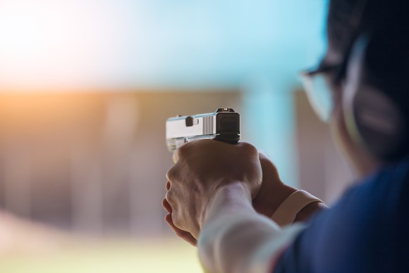 A person firing a pistol at a shooting range.
