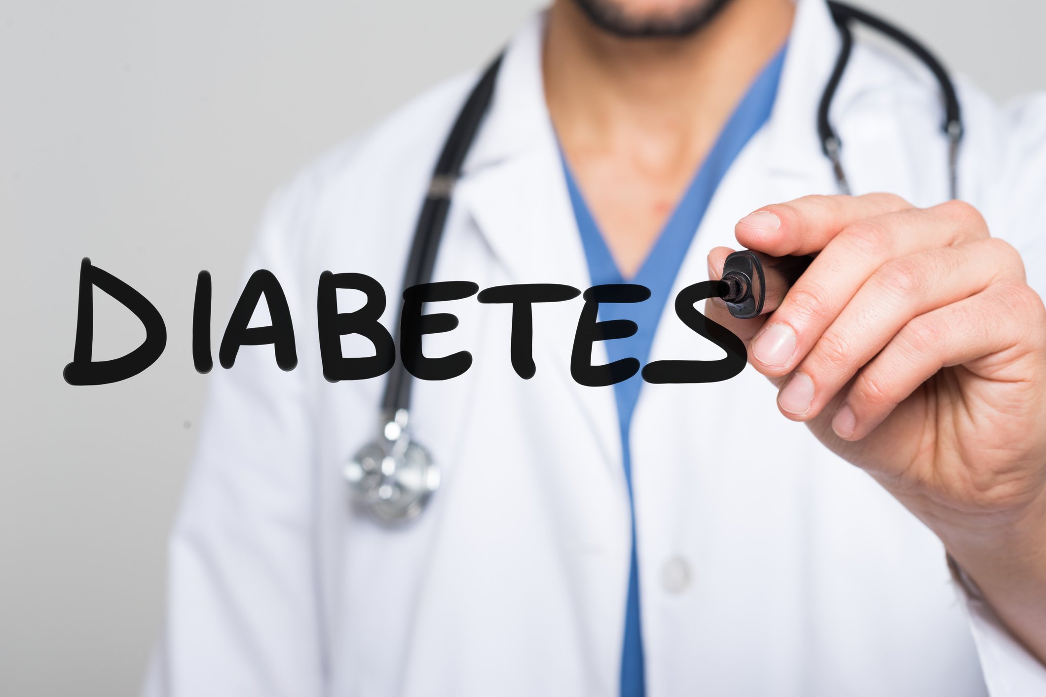 Doctor holding marker up to the word "diabetes" written on glass