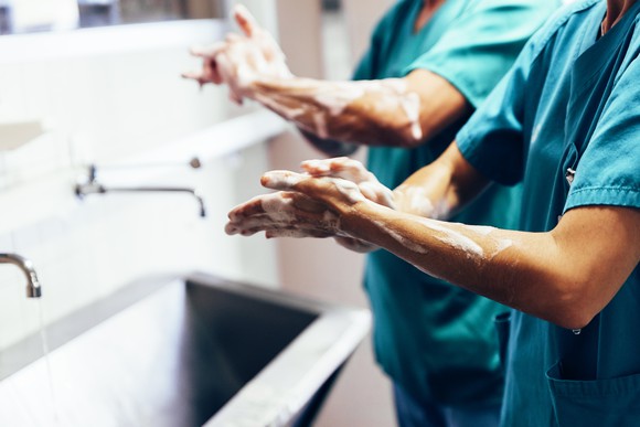 SUrgeons in green scrubs washing hands