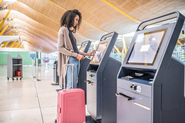 A woman checks in at an airport kiosk