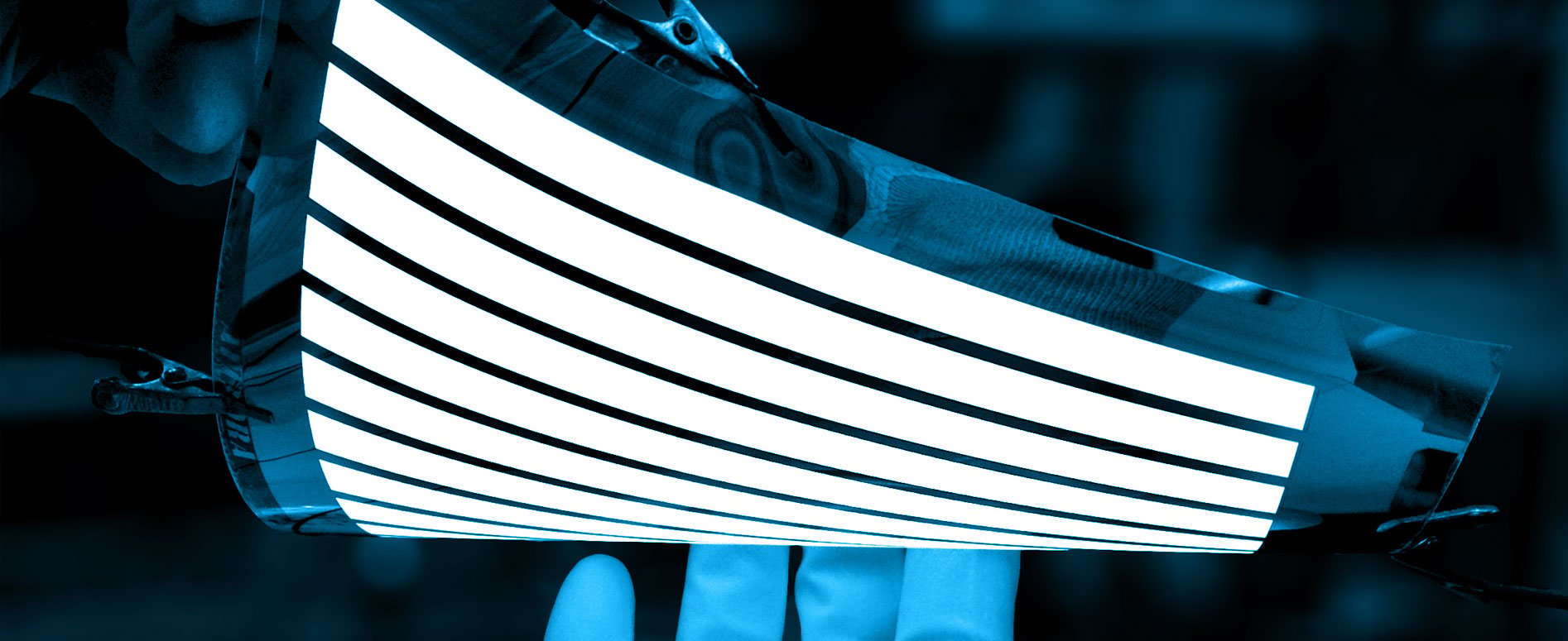 A technician flexes a bendable OLED screen while showing a simple image.