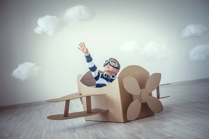 A child playing pretend in a cardboard box made as an airplane.