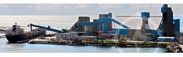 Processing plant and cargo loading facilities on a lake, with a ship taking on cargo.