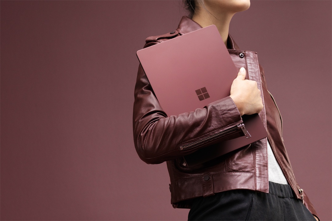 A woman carries a Surface Laptop.