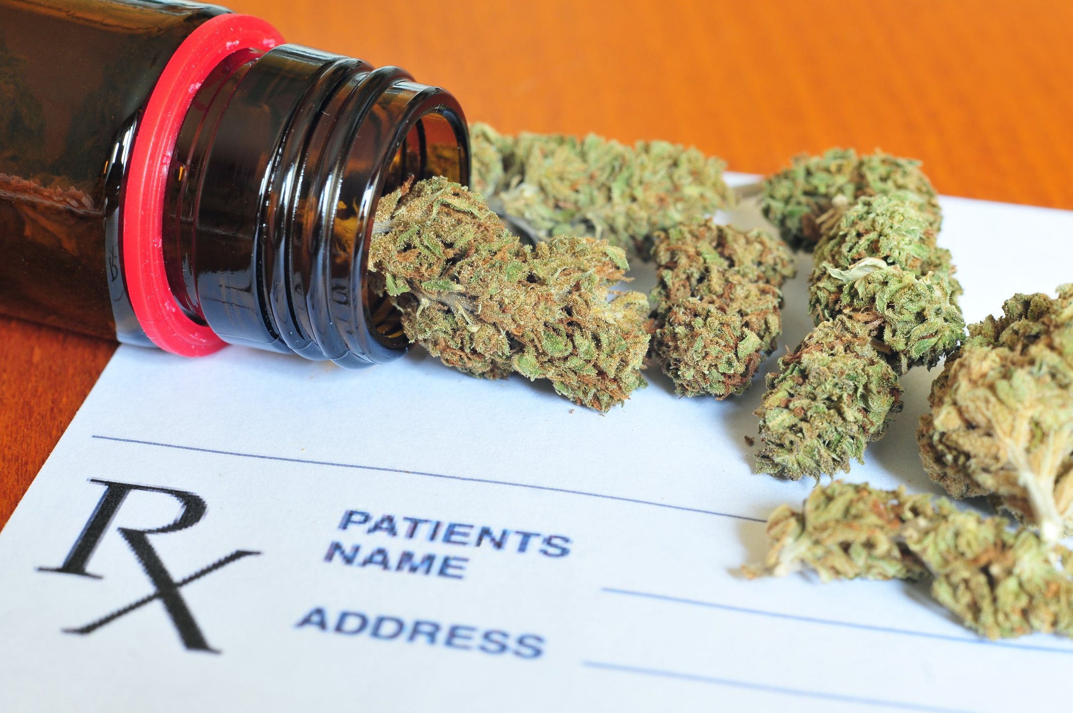 Marijuana buds spilling out of bottle on top of a prescription form
