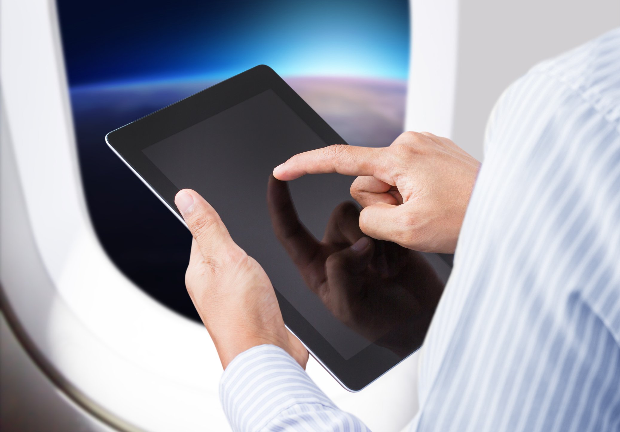 A man uses a tablet on a plane.