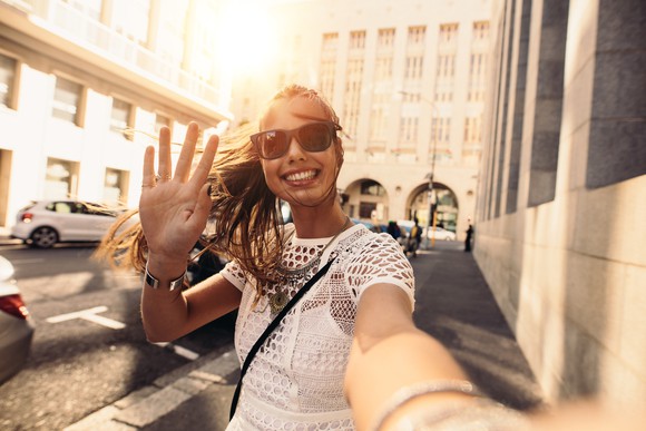 A woman takes a selfie on a street.