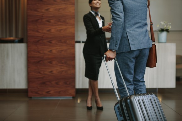 A man being greeted at hotel entrance by a female hotel employee. 