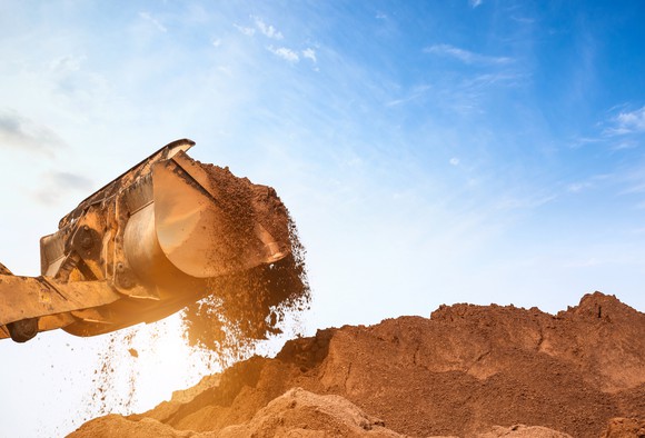 A shovel filled with sand from a big pile.