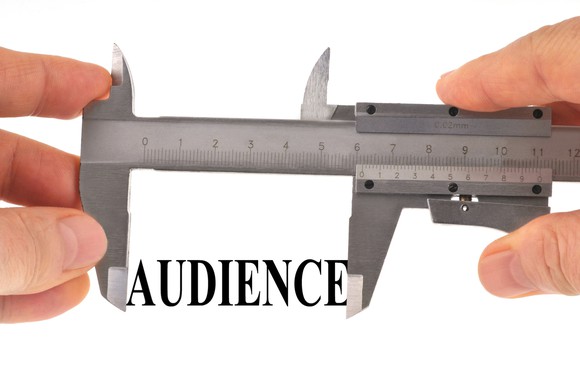 Abstract concept of audience measurement: A pair of calipers measuring the word "audience."