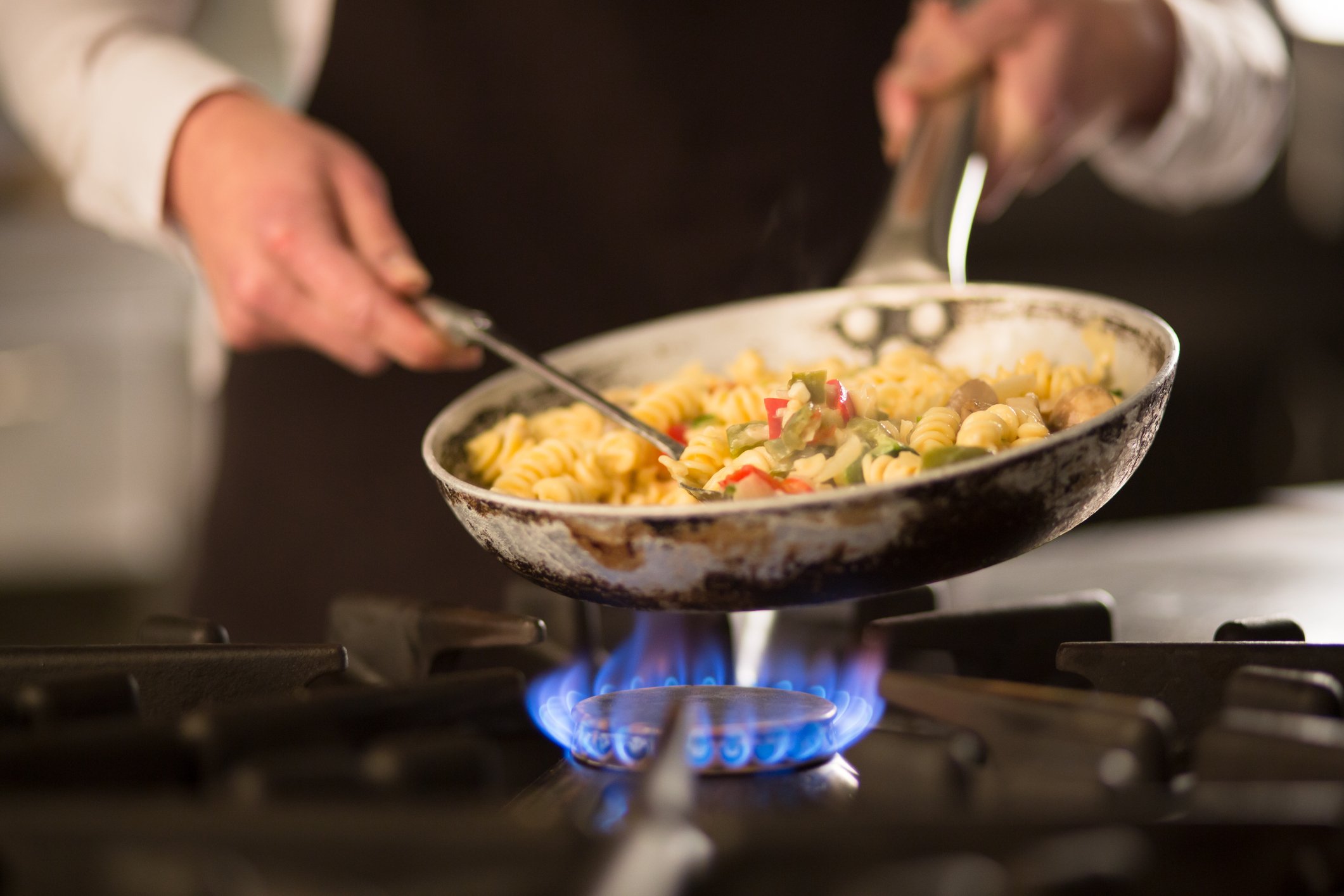 Chef cooking pasta on a commercial range