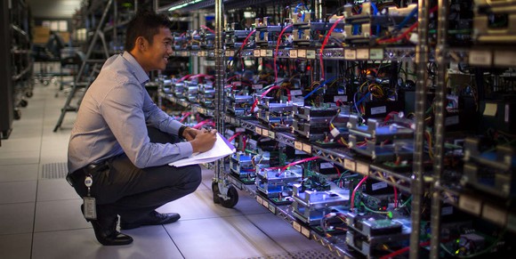 A man kneels to inspect an array of Western Digital storage drives