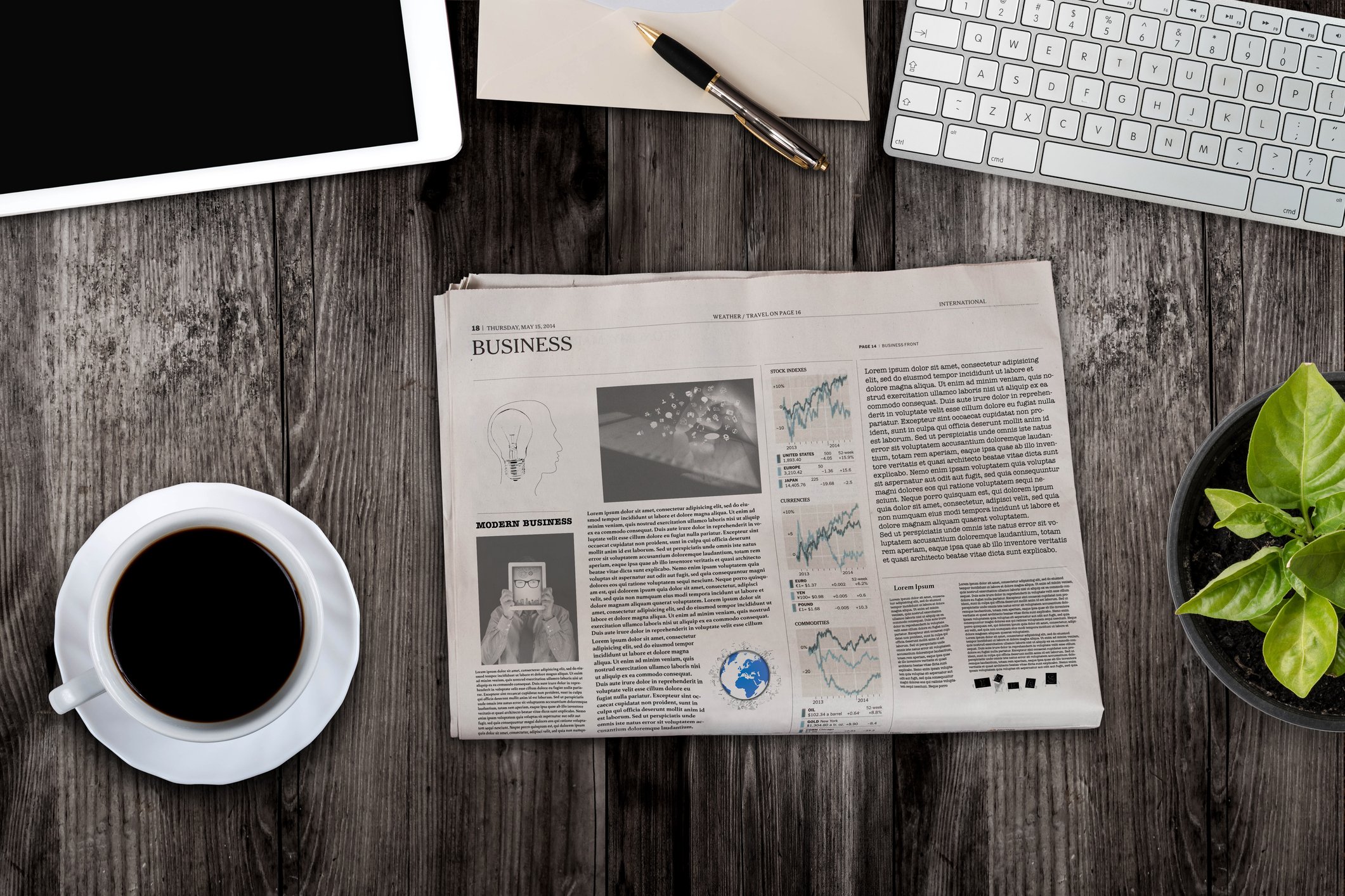 A newspaper next to a cup of coffee on a desk
