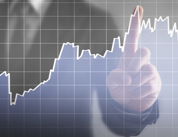 Hand pointing to rising stock graph.