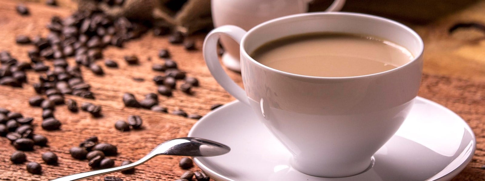 A cup of coffee with coffee beans in the background.