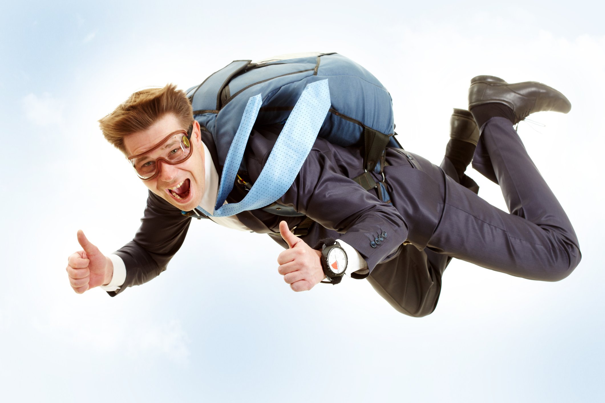 A man in a suit falling in the sky while wearing a parachute.