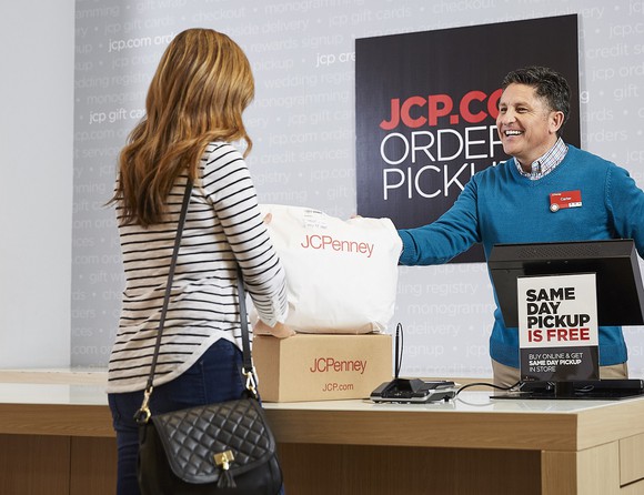 Shopper at J.C. Penney order pickup desk with two packages from the sales clerk.