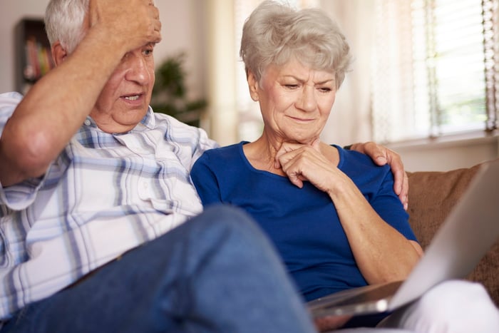 Older man and woman frown at a computer screen.