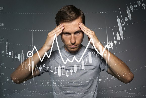 Man with hands on his forehead with ascending stock chart in front of him