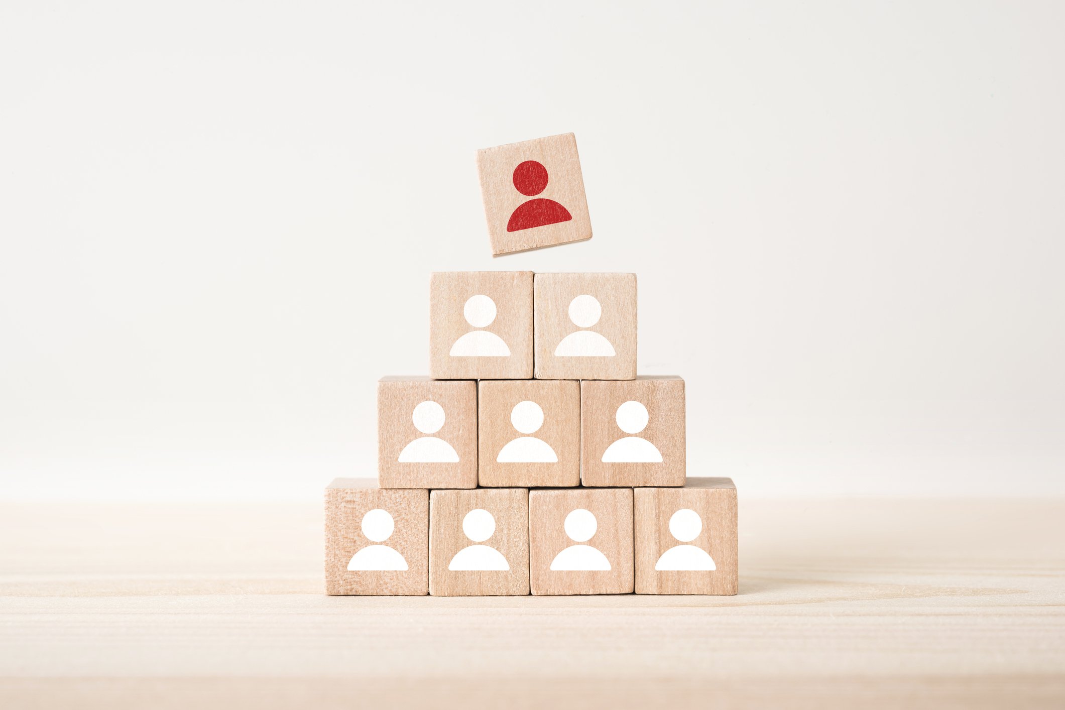 A pyramid made of 10 blocks with symbols of people on them, and the highest block is red