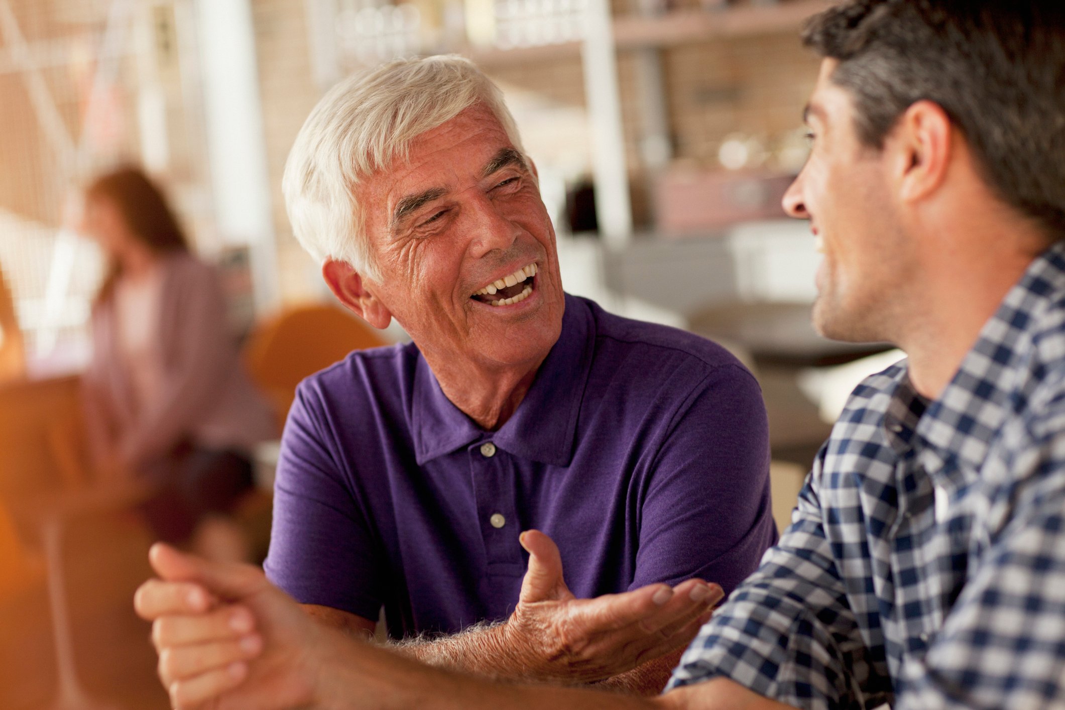An older man and a younger man having a discussion in a coffee shop.