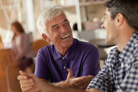 An older man and a younger man having a discussion in a coffee shop.