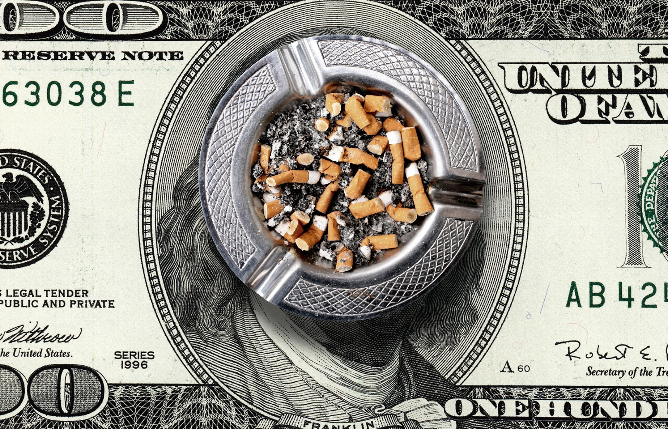 Full ash tray on top of a giant hundred dollar bill.