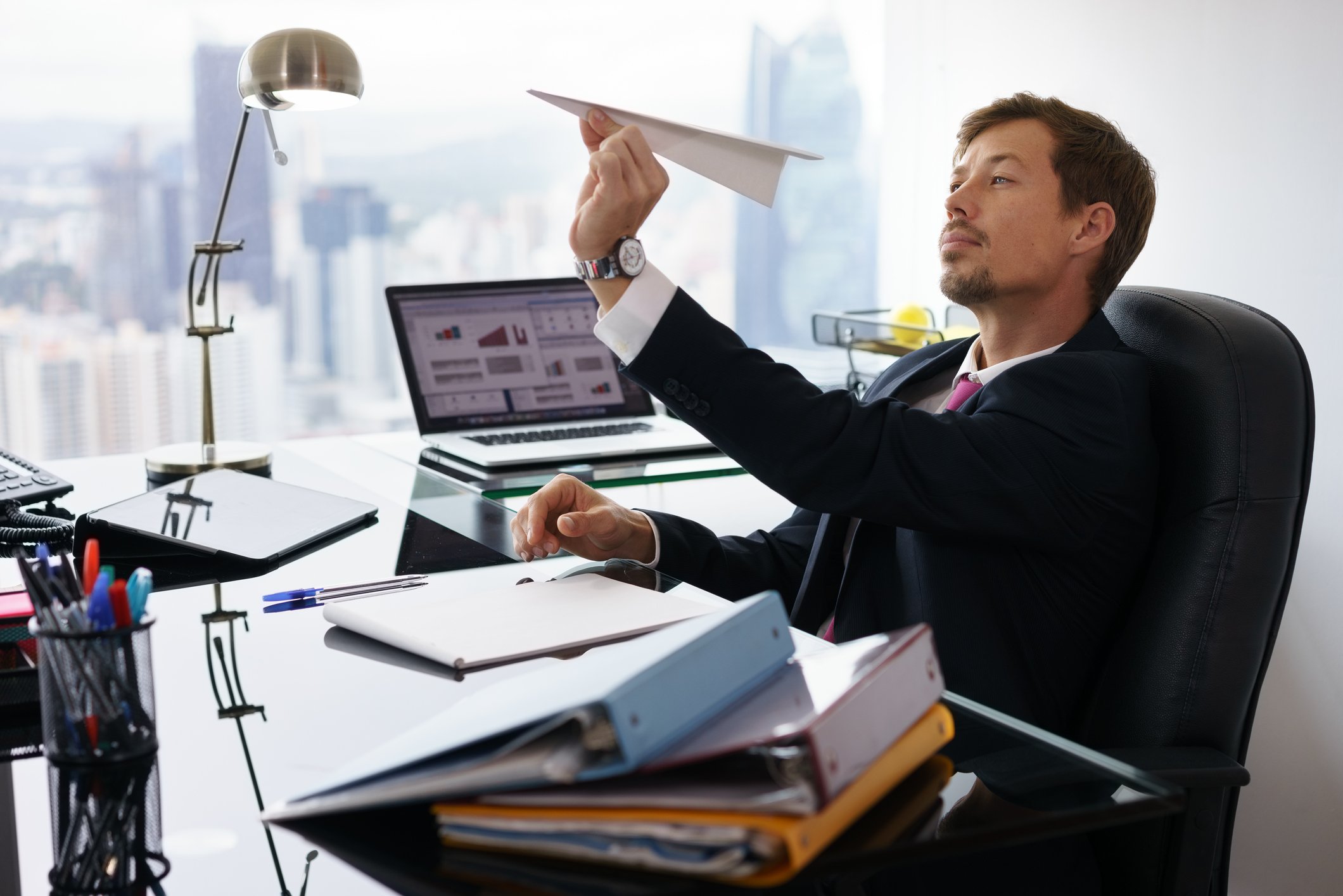 A person is holding a paper airplane at a desk.