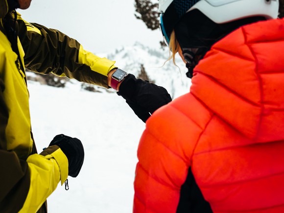A skier looking at an Apple Watch