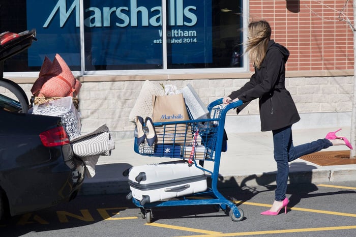 A woman with a shopping cart outside of a Marshalls store