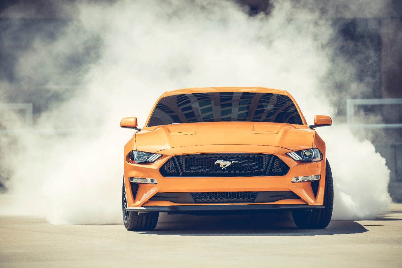 Orange Mustang with smoke coming from rear tires
