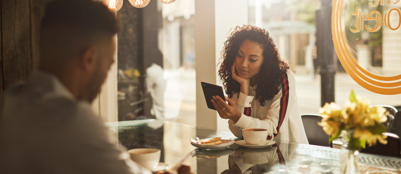 A woman using an e-reader with coffee on the table.