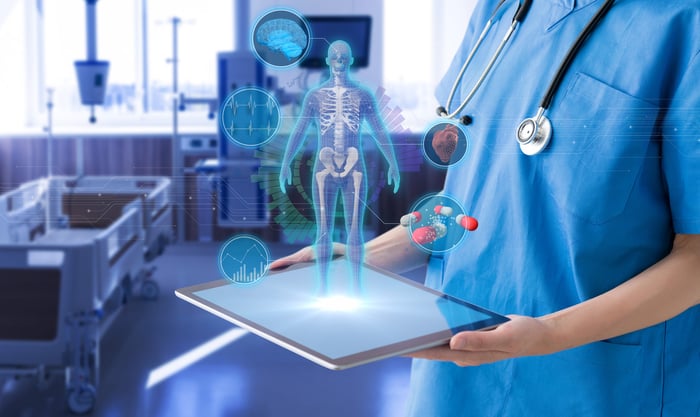 Doctor holding a tablet in a hospital room, with medical images emerging from the tablet