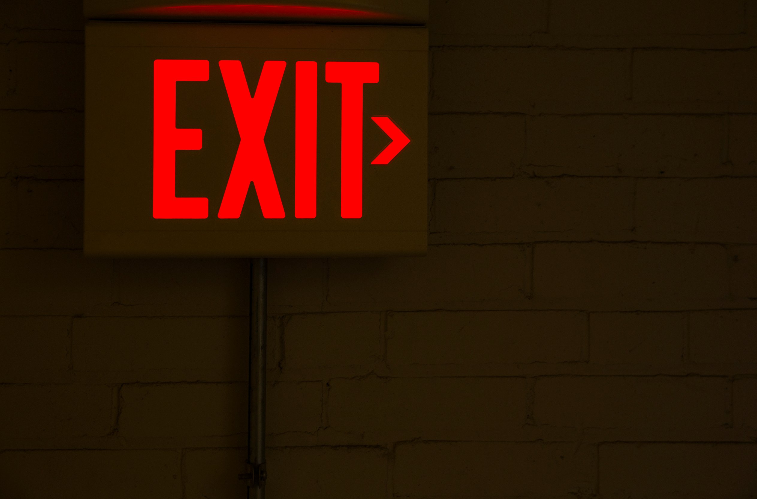 An illuminated exit sign on a wall in a dark room.