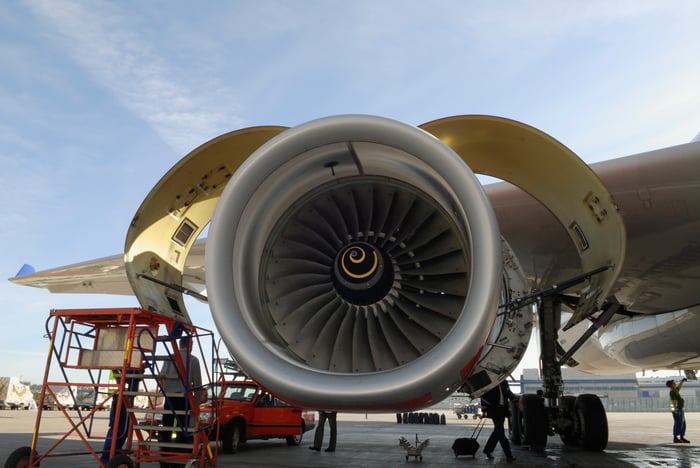 A jet engine being inspected on the tarmac.