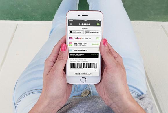 A person holds a smartphone with the Kohl's app loaded.