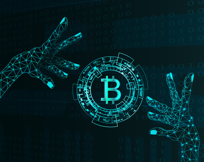 Pair of electronic hands and bitcoin symbol