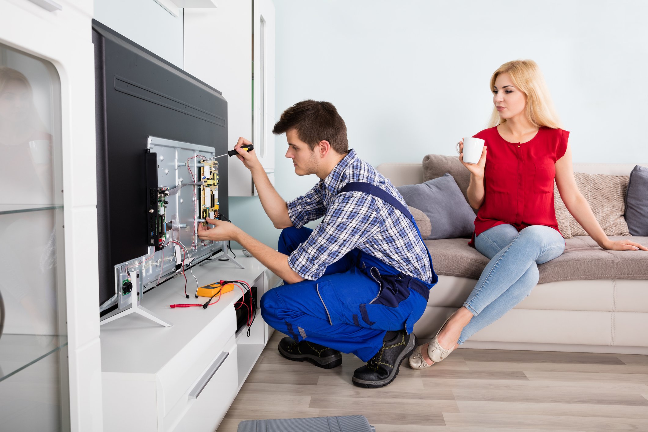 Woman watches handyman installing a TV