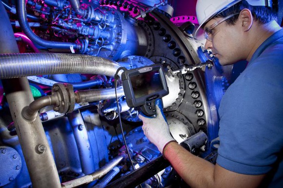 A man in a hard hat inspects a power turbine unit