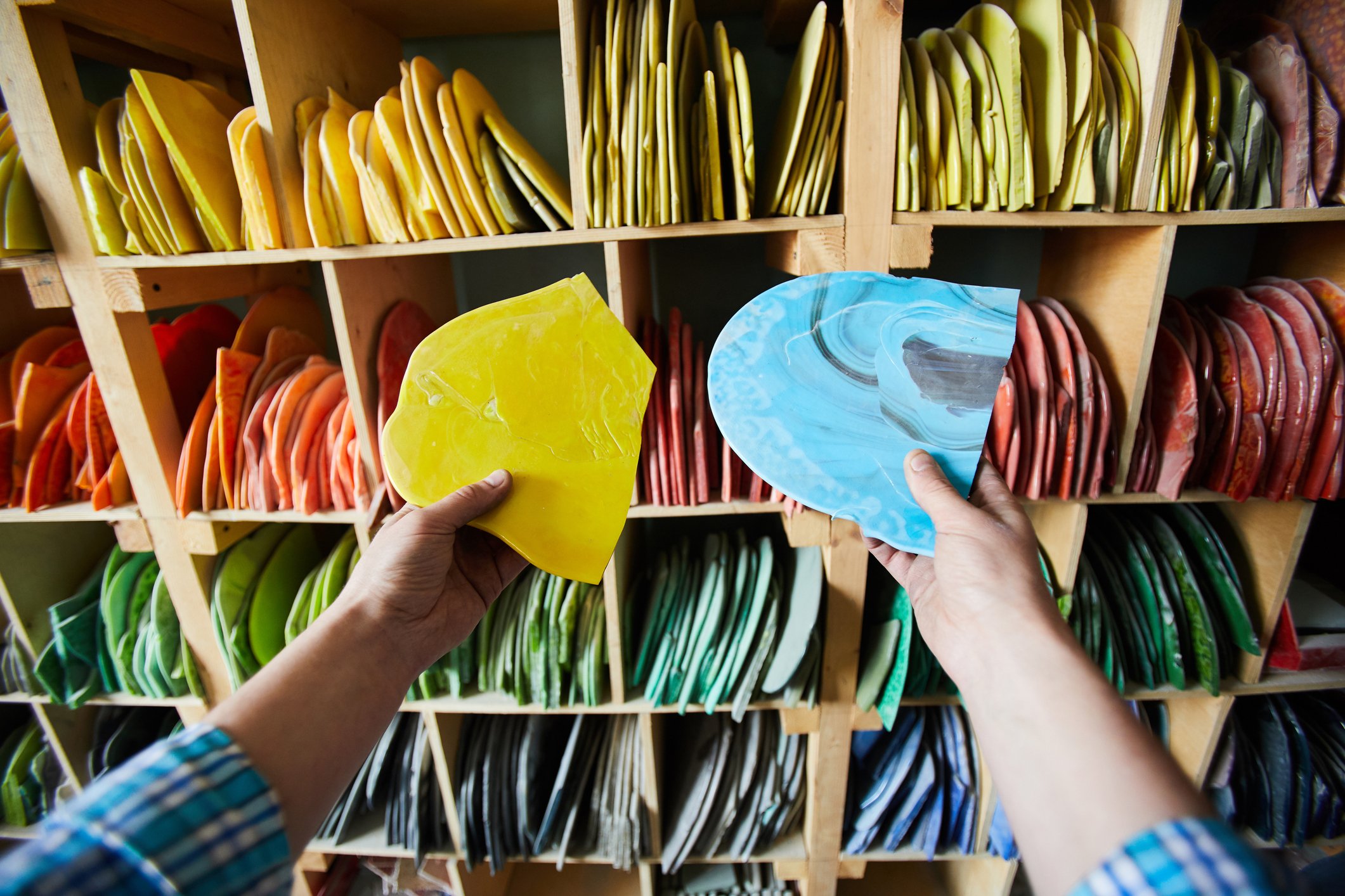 A person picking out colorful pieces of crafting material from a rack of shelves.