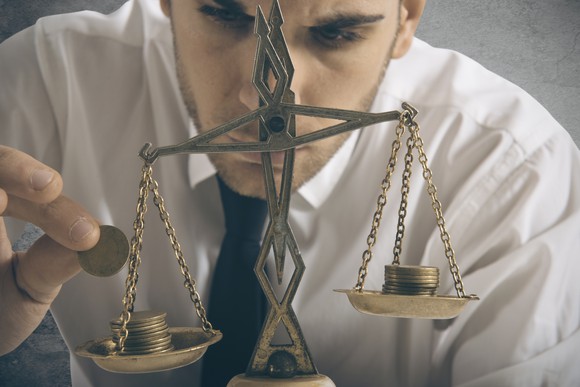 A businessman is weighing coins on a set of old-school scales.