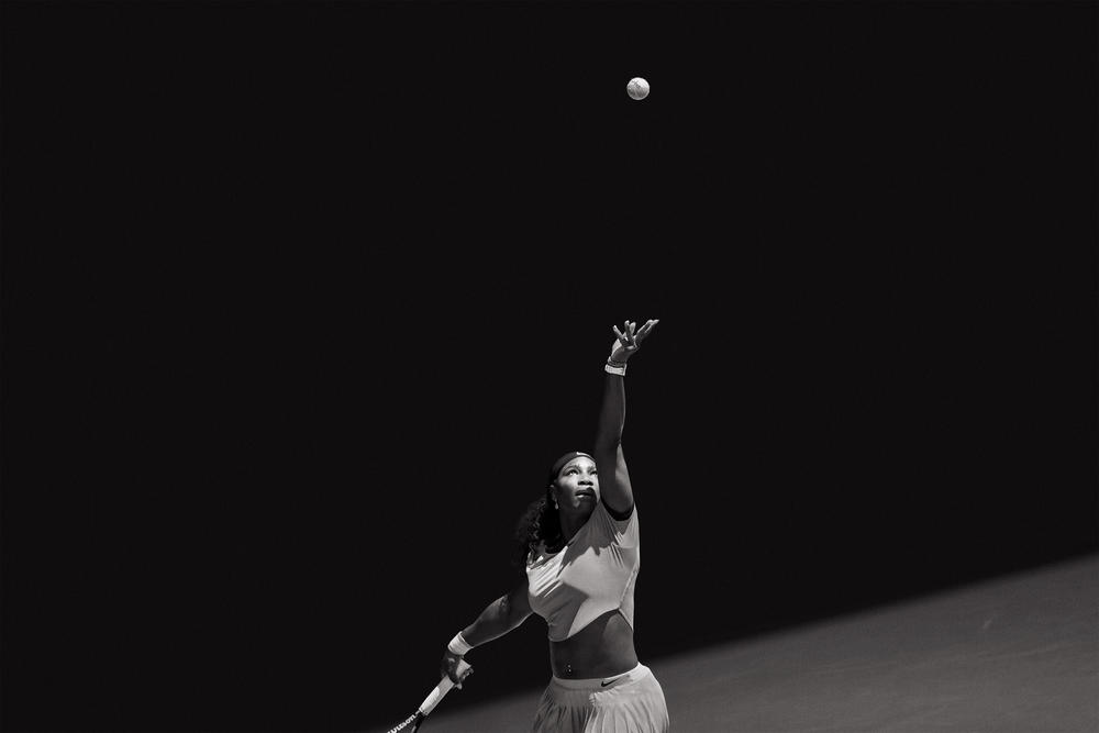 Serena Williams tossing a ball as she prepares for a serve.
