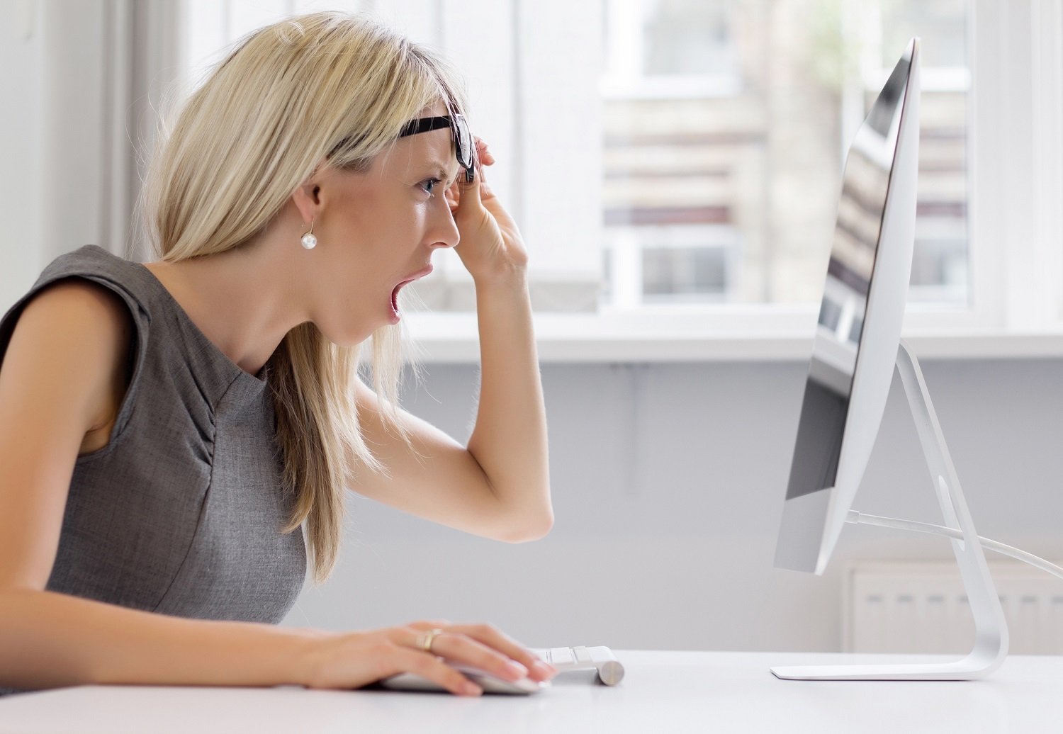 Woman looks at computer screen with shocked expression.