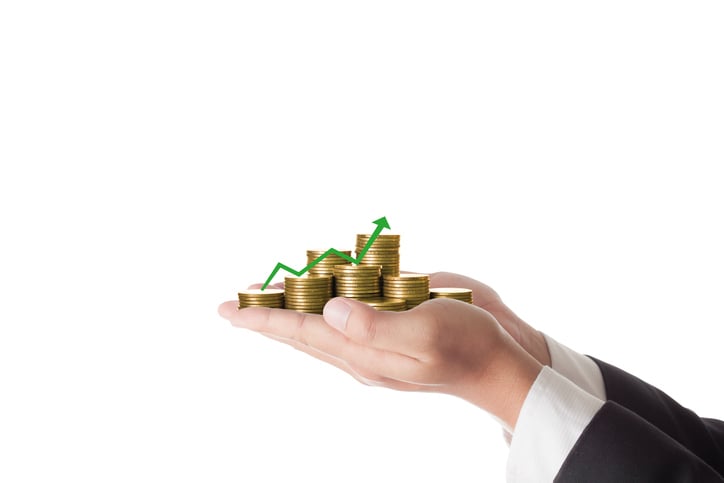 Hands holding stacks of coins and green arrow pointing up.
