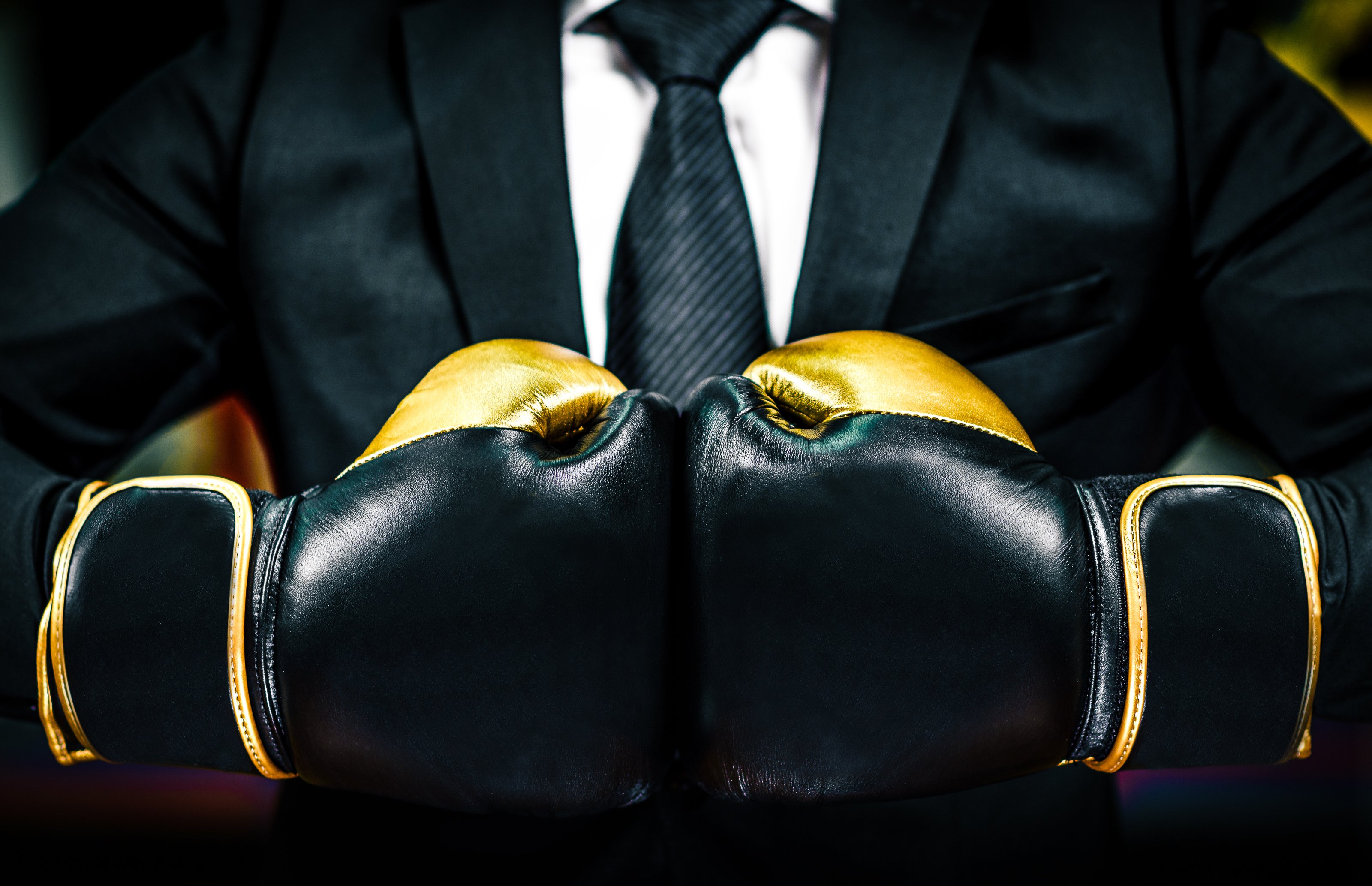 A person in a business suit wearing boxing gloves